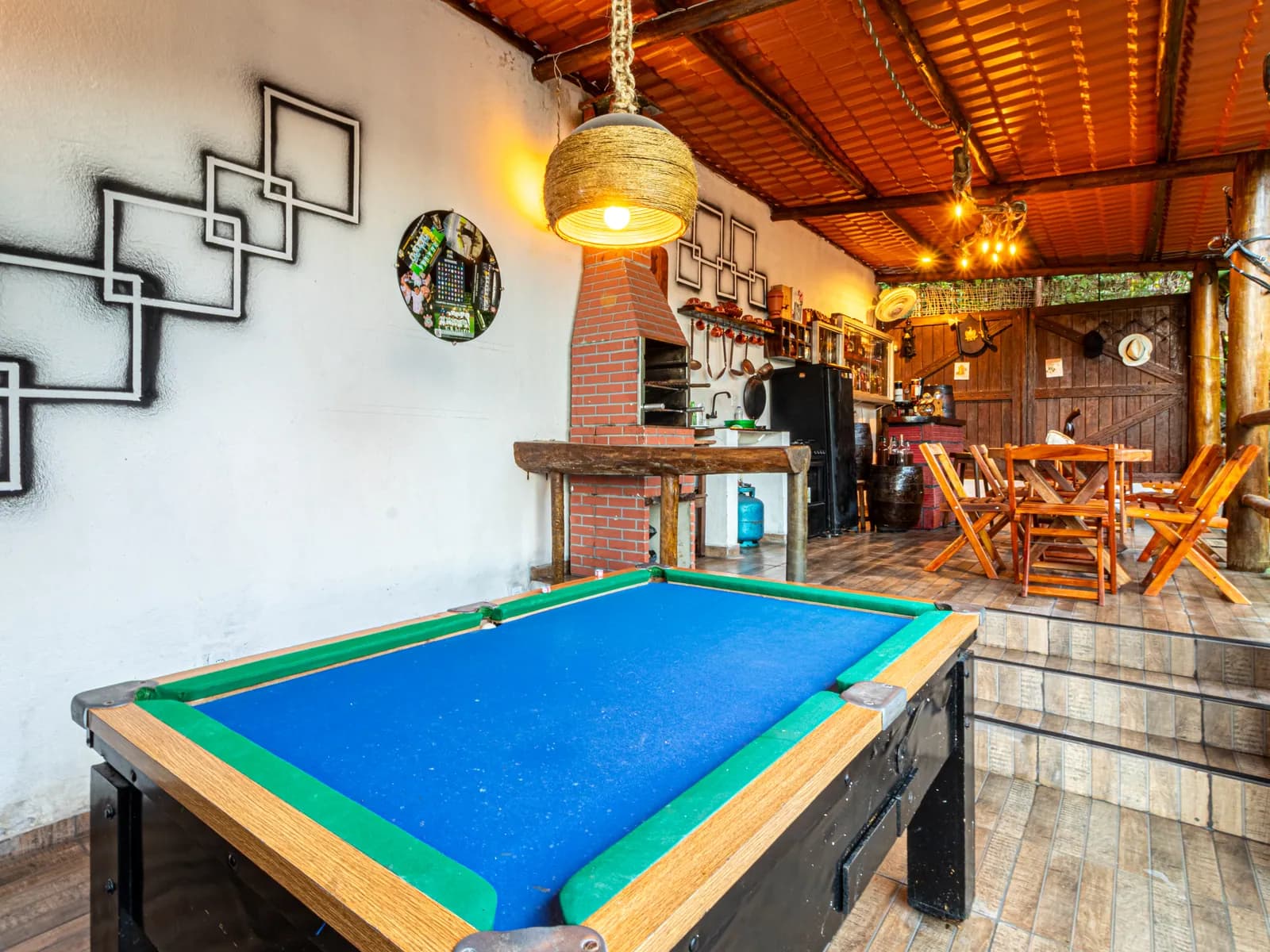 Sala de jogos da Casa 1 com mesa de sinuca e churrasqueira