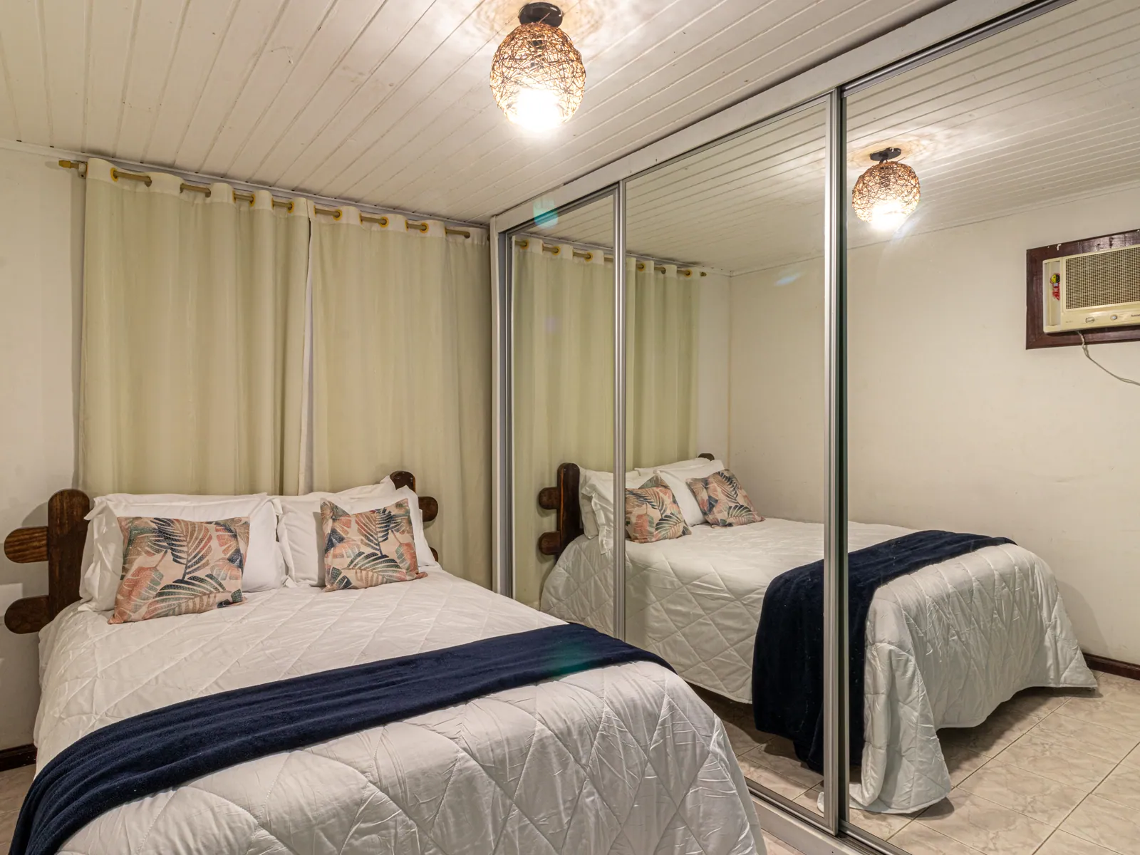 Suíte principal da Casa 1 com cama de casal e espelho