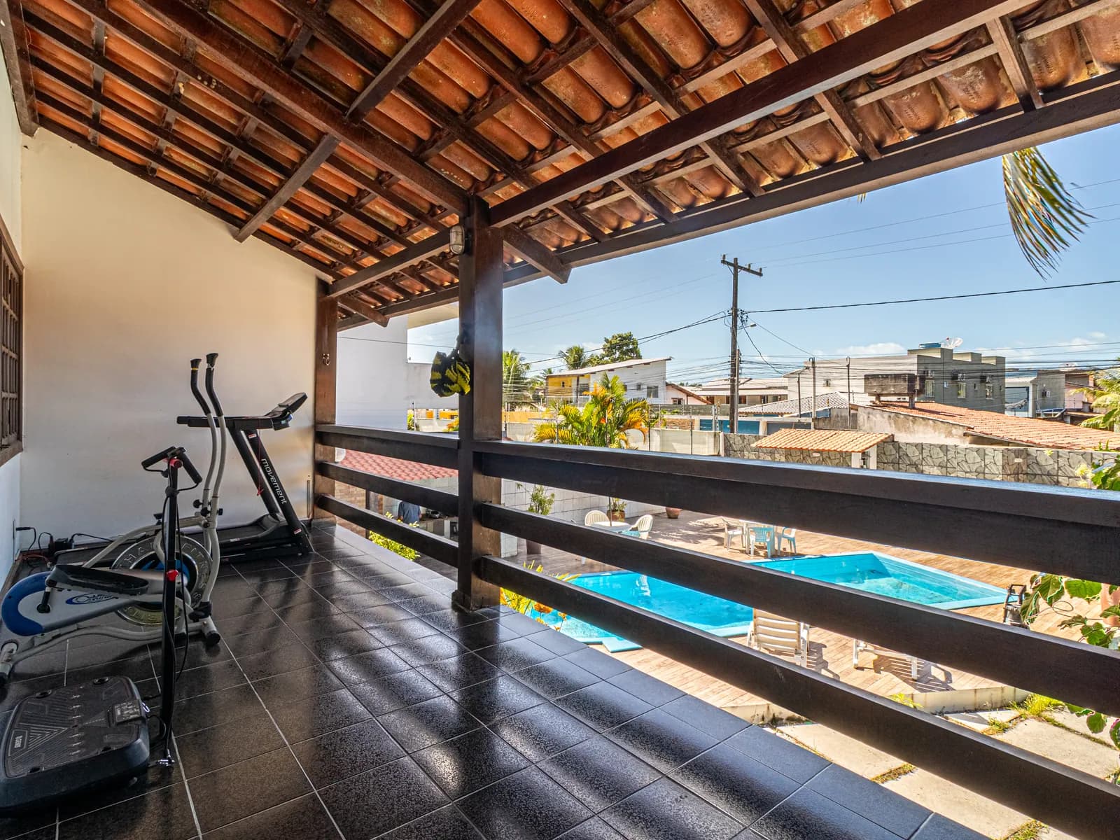 Varanda da Casa 1 com equipamentos de ginástica e vista para a piscina