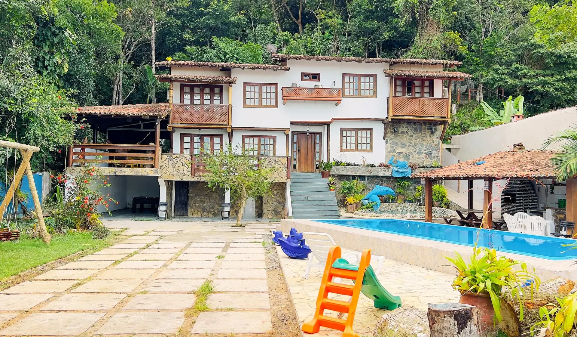 Fachada da Casa 2 com a piscina comprida e o playground no pátio