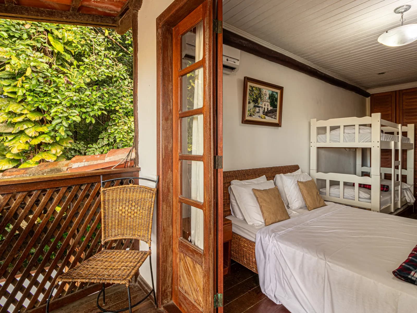 Quarto da Casa 2 com porta aberta para a varanda e a mata