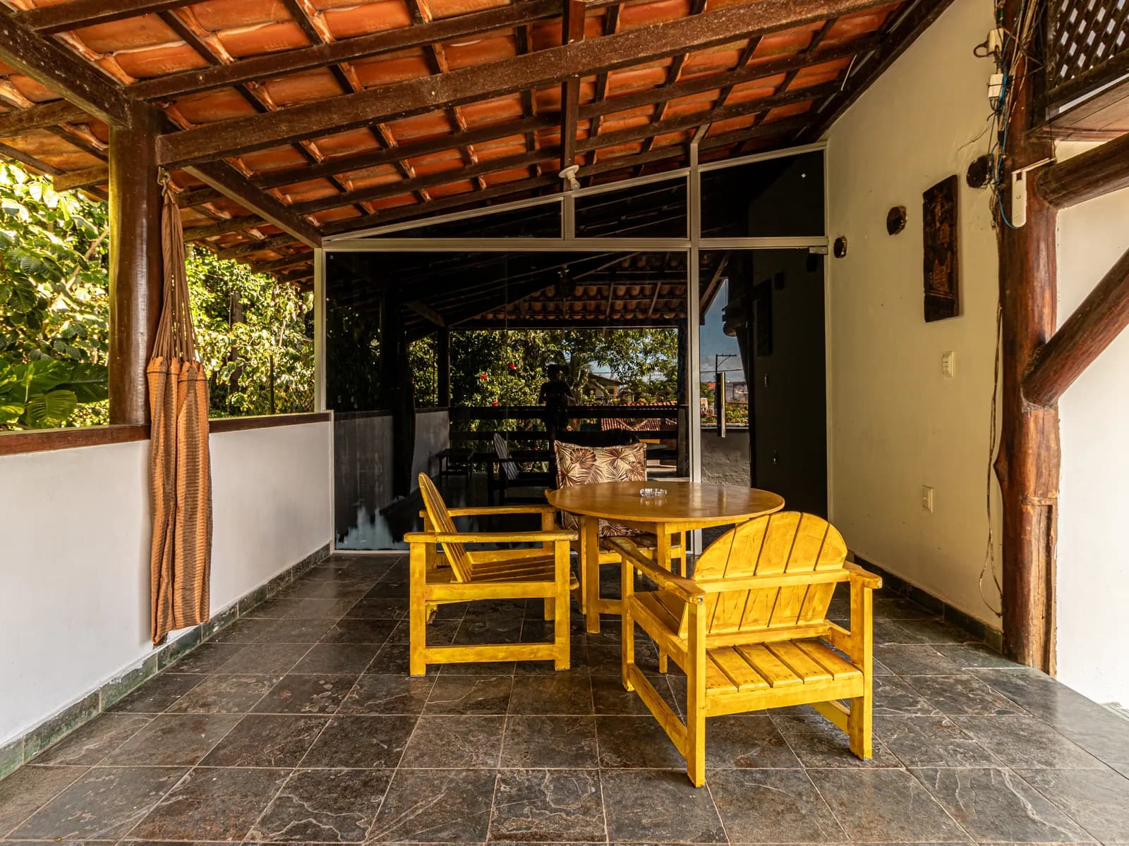 Varanda da Casa 2 com cadeiras amarelas e vista para a mata