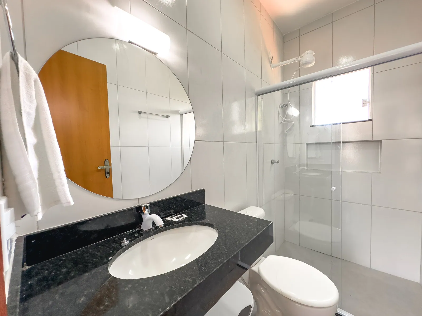 Banheiro do apartamento com bancada de granito e box de vidro
