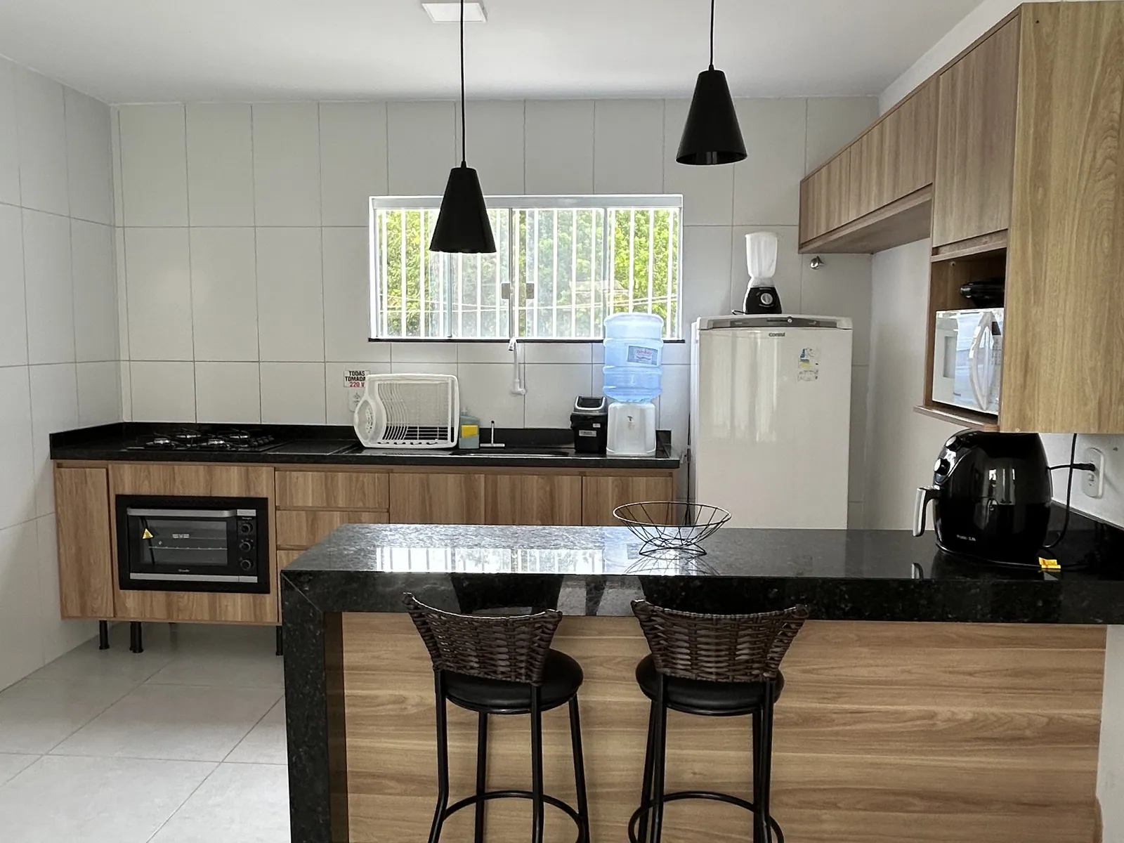 Cozinha americana do apartamento com bancada de granito e banquetas