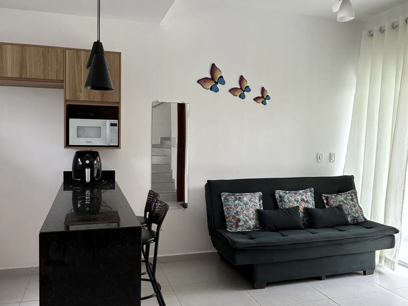 Sala do apartamento com sofá-cama e porta de vidro para o jardim