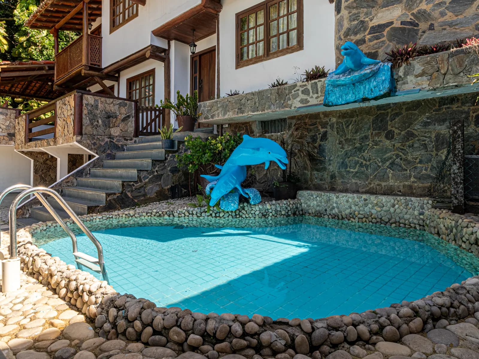 Piscina redonda da Casa 2 com cascata e jardim de pedras