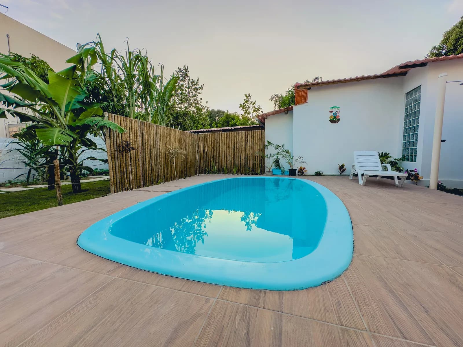 Piscina do condomínio com deck de madeira e espreguiçadeiras