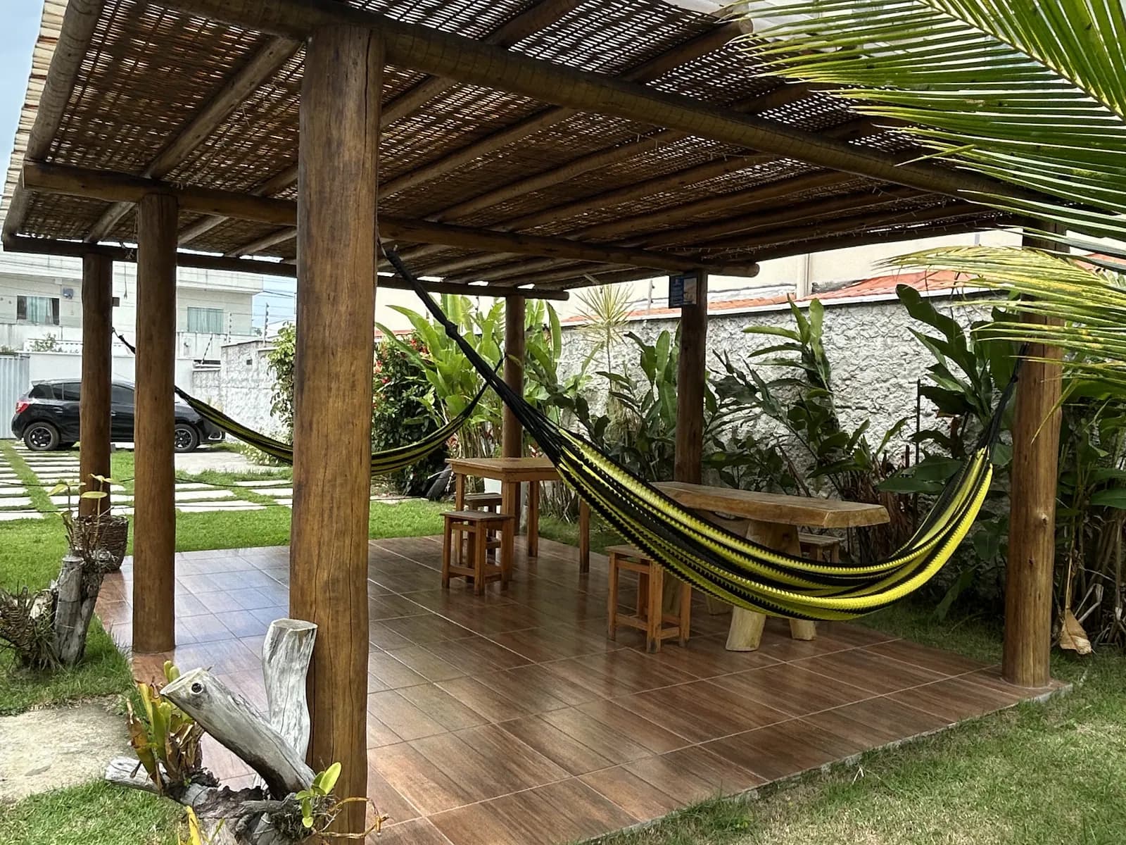 Redário sob pergolado de bambu no jardim do condomínio