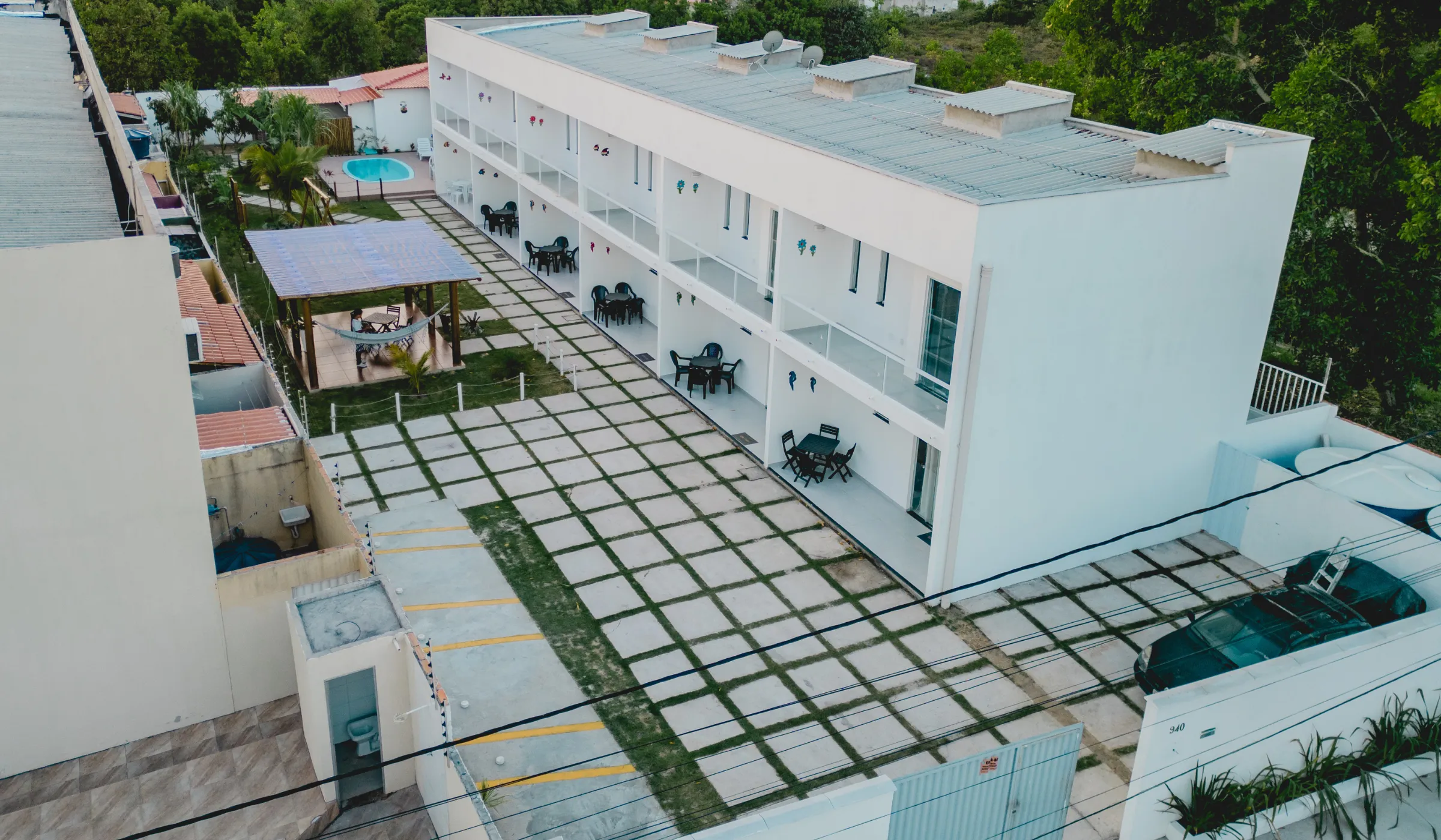 Jardim central do Village Mariah Condomínio ao entardecer, com os apartamentos ao fundo