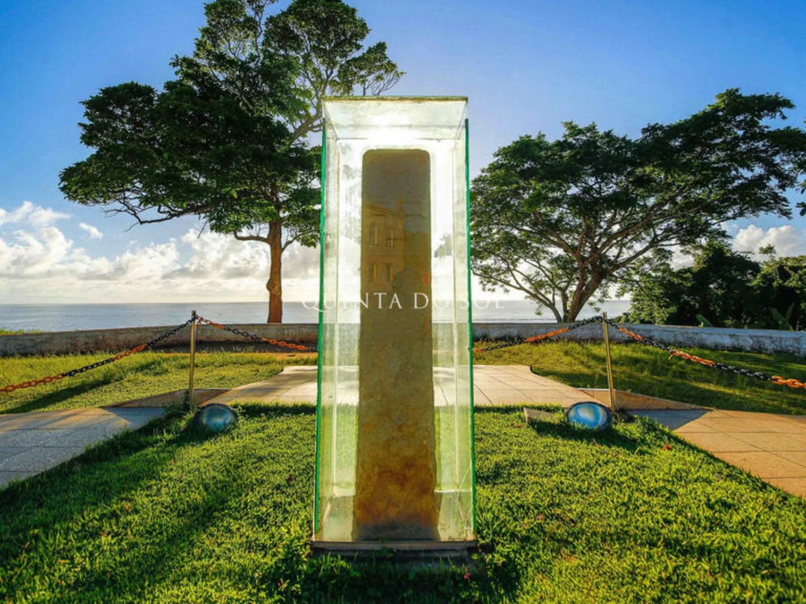 Marco do Descobrimento em vitrine de vidro na Cidade Alta de Porto Seguro, com o mar ao fundo