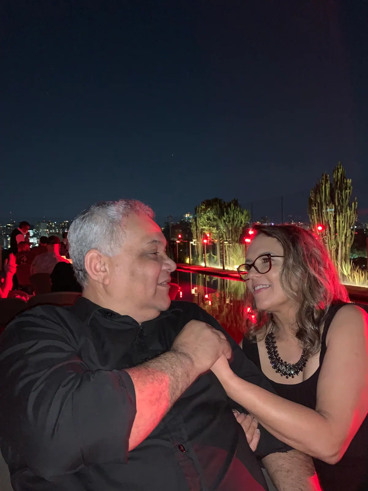 Anfitriões do Village Mariah, um casal, em um ambiente externo à noite